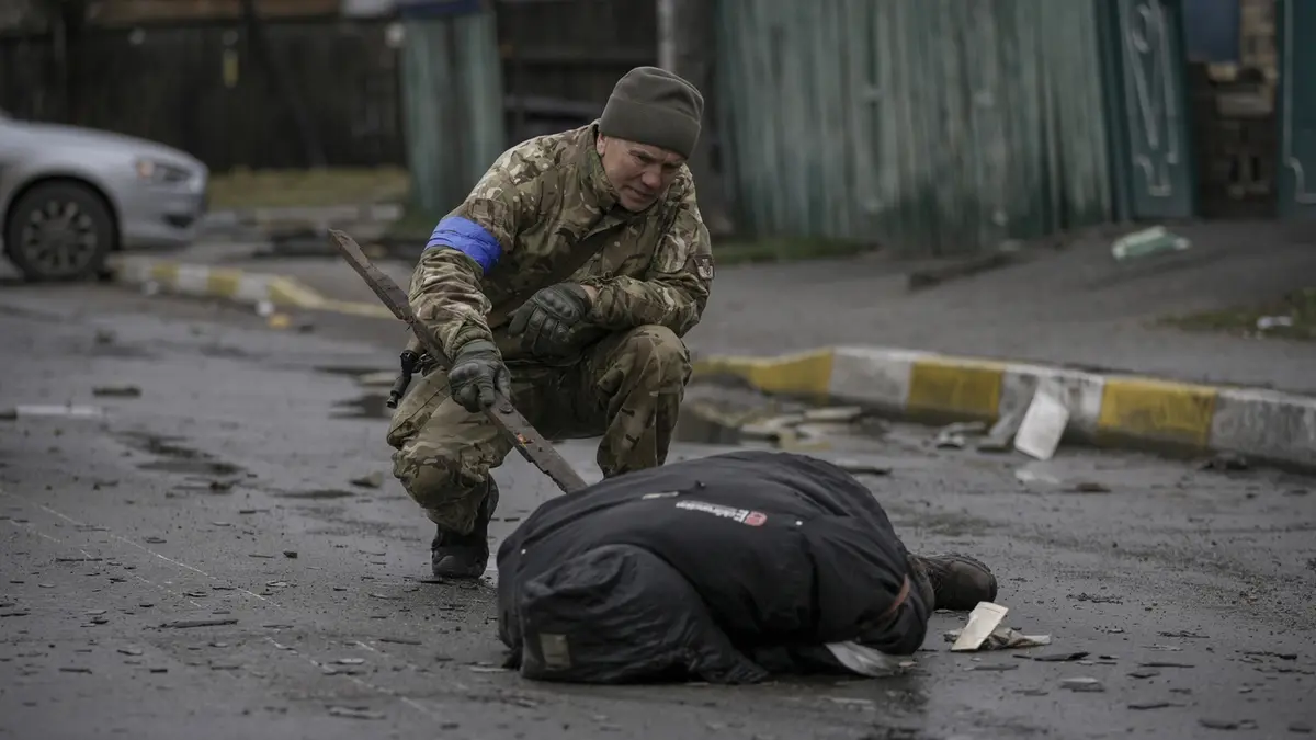 Ukrajinský voják kontroluje tělo jednoho z civilistů kvůli zprávám, že Rusové podminovali právě i mrtvá těla.