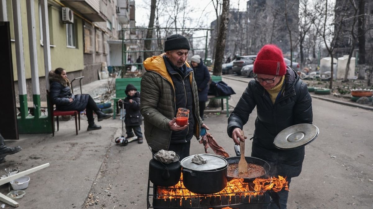 Lidé vaří jídlo v ulicích Mariupolu.