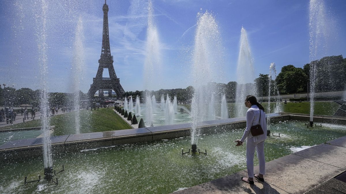 Žena se chladí u fontány v zahradě Trocadero u Eiffelovy věže v Paříži, čtvrtek 16. června 2022. Očekává se, že horké počasí bude v celé zemi trvat několik dní.