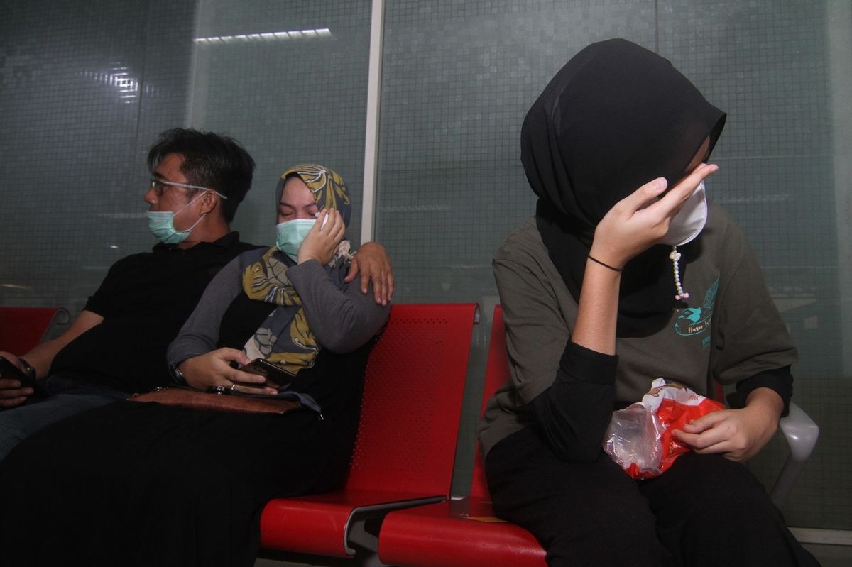 Příbuzní a přátelé cestujících se na letišti modlí a pláčou.