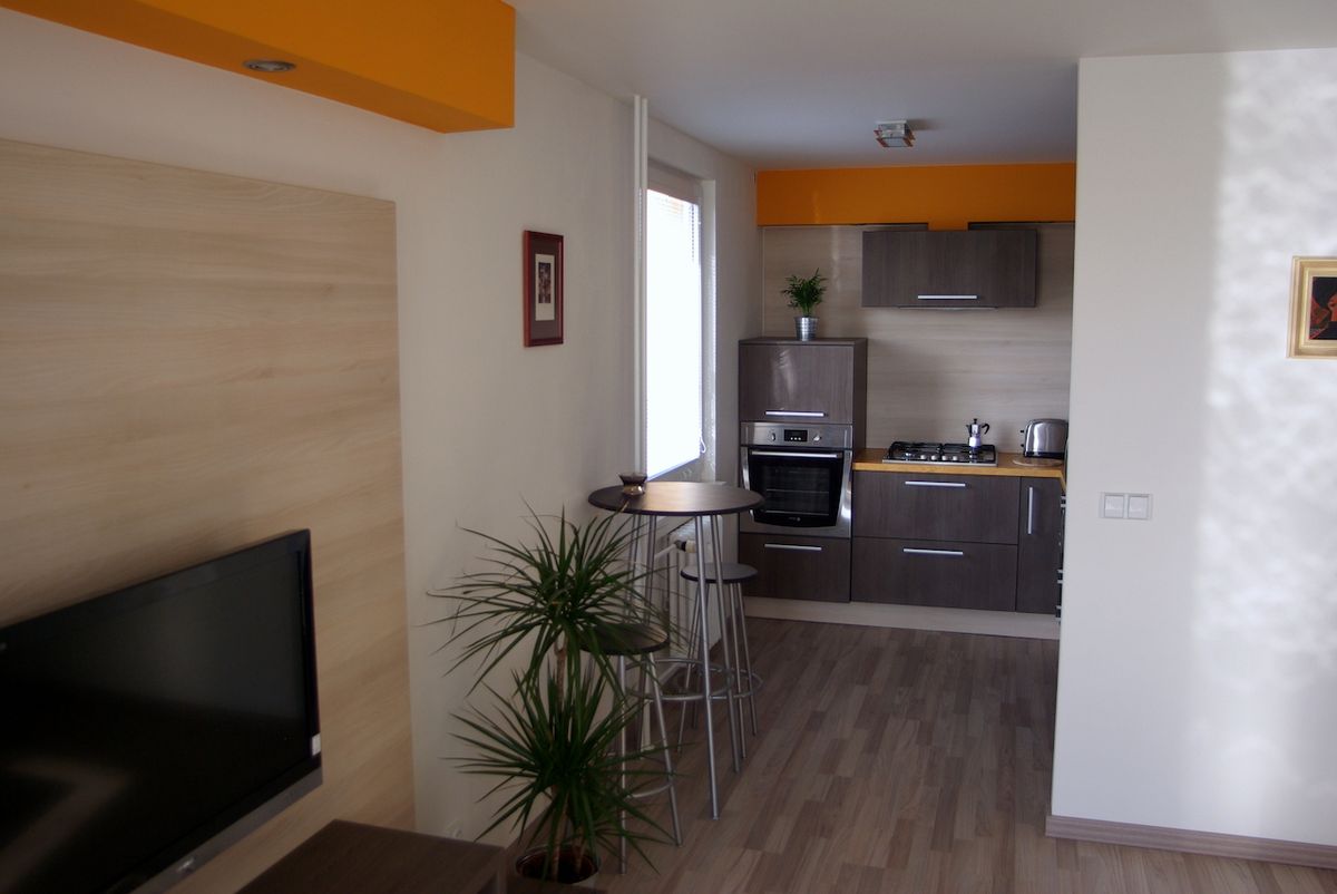 Tmavé dřevo a oranžová barva se vyskytují v obývacím pokoji i kuchyni.