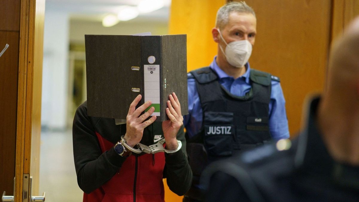 Táhá al-Džumajlí si zakrývá obličej při příchodu do soudní síně.