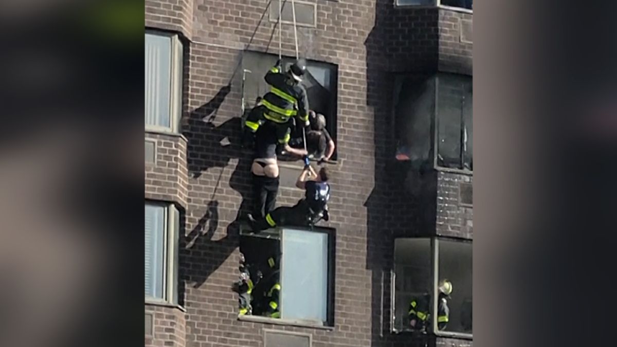 Ženě visící na okně hořícího domu hasiči nechtěně stáhli kalhoty