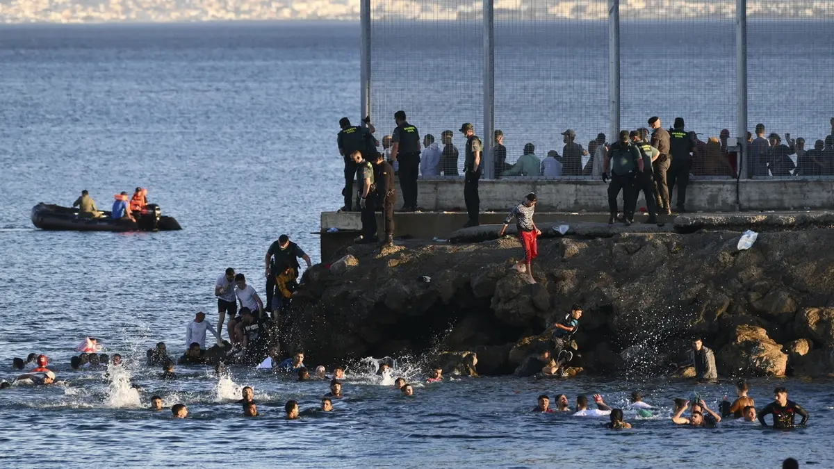 Španělští gardisté se snaží zabránit migrantům z Maroka, kteří připlavali, aby vstoupili na území Ceuty.