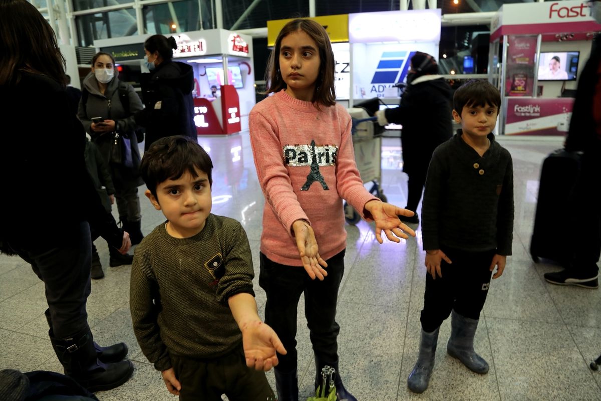 Děti vracejících se migrantů ukazují na irbílském letišti rány a boláky na rukou. 
