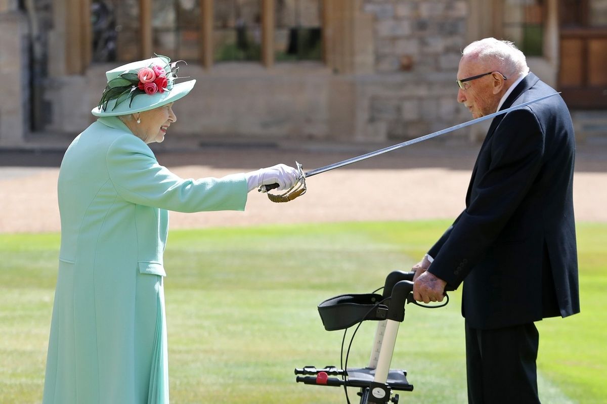 Královna Alžběta II. povyšuje Toma Moorea do rytířského stavu.