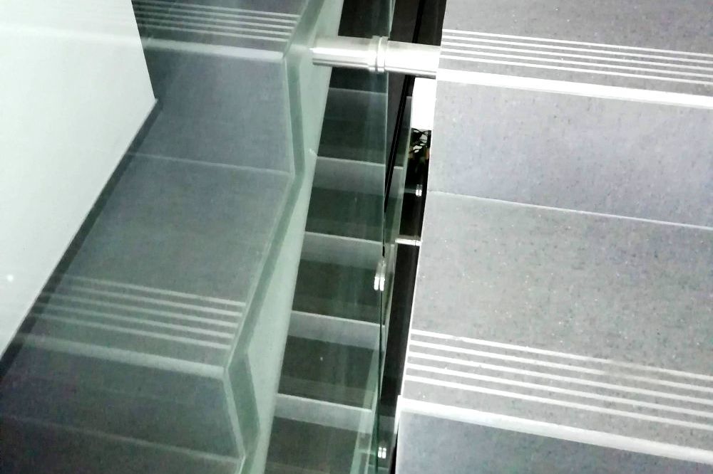 Moderní, vzdušné schodiště v bytovém domě se zábradlím ze skleněných desek nesplňuje bezpečnostní předpisy.