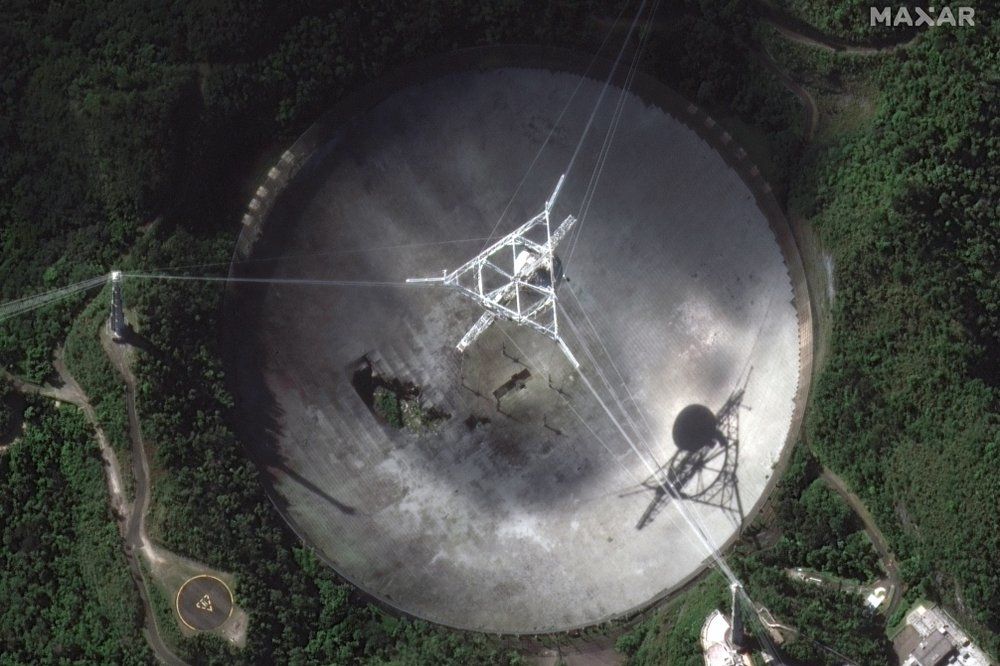 Satelitní snímek poškozené observatoře Arecibo - fotografie s trhlinou v disku je z poloviny listopadu, tedy ještě před definitivním zhroucením radioteleskopu.