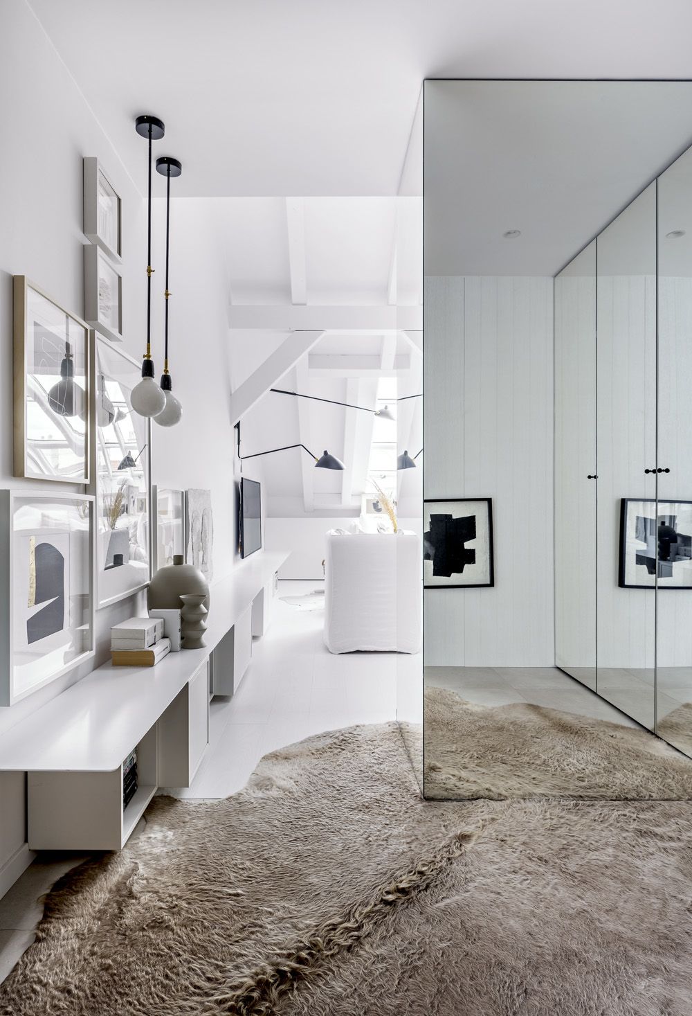 Úložné prostory ve vstupní chodbě jsou opatřeny dveřmi se zrcadly. Bíle lakované police z kovu v celkové délce sedmi metrů jsou vyrobené na míru a doplněné typovými nábytkovými skříňkami různých hloubek (IKEA).