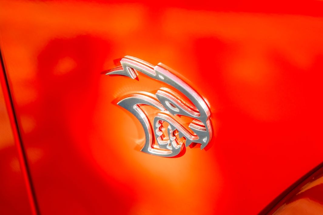 Logo Hellcat („Pekelná kočka”) za předním kolem Dodge Challenger znamená 716k kompresorový osmiválec pod kapotou. (Ilustrační foto)