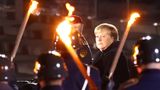 Merkelová se za svitu ohňů a zpěvu armády rozloučila s funkcí