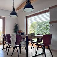 Velký jídelní stůl pro osm osob doplňují pohodlné koženkové židle.