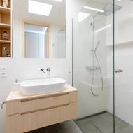 Koupelně dominuje bílá barva a světlé dřevo.