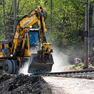 Stroj odhrnuje přebytečný materiál z druhé koleje mezi Karlštejnem a Srbskem.