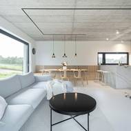 Velká okna mají černé rámování, které oživuje jinak striktně světlý interiér.