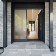 Do moderního domu rodina vchází skrze hliníkové vchodové dveře v antracitovém odstínu s madlem o prodloužené délce 1,6 metru.