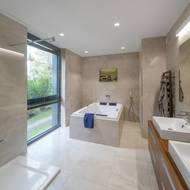 Koupelny jsou laděny decentně a elegantně díky kombinaci světlých béžových tónů keramického obložení spolu s dřevěnými úložnými skříněmi a bílým sanitárním vybavením.