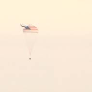 Přistávající návratový modul Sojuz MS-26 nad stepí v Kazachstánu