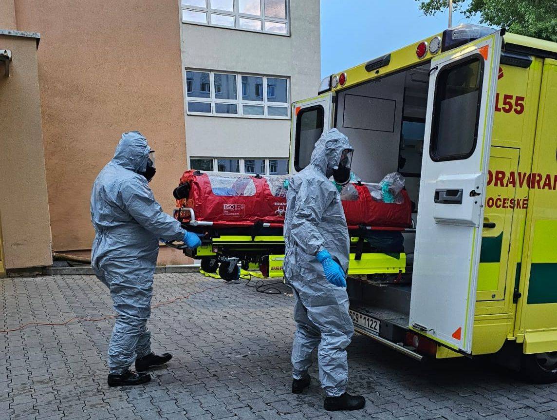 Biohazard tým nakládá pacienta do sanitky, která je vybavená filtrační jednotkou