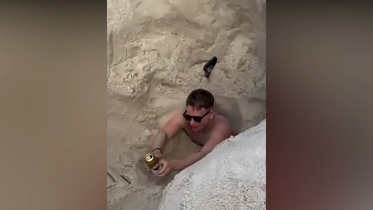 Turista na pláži uvázl v jámě, kterou si sám vykopal. Při vyprošťování si dal i pivo