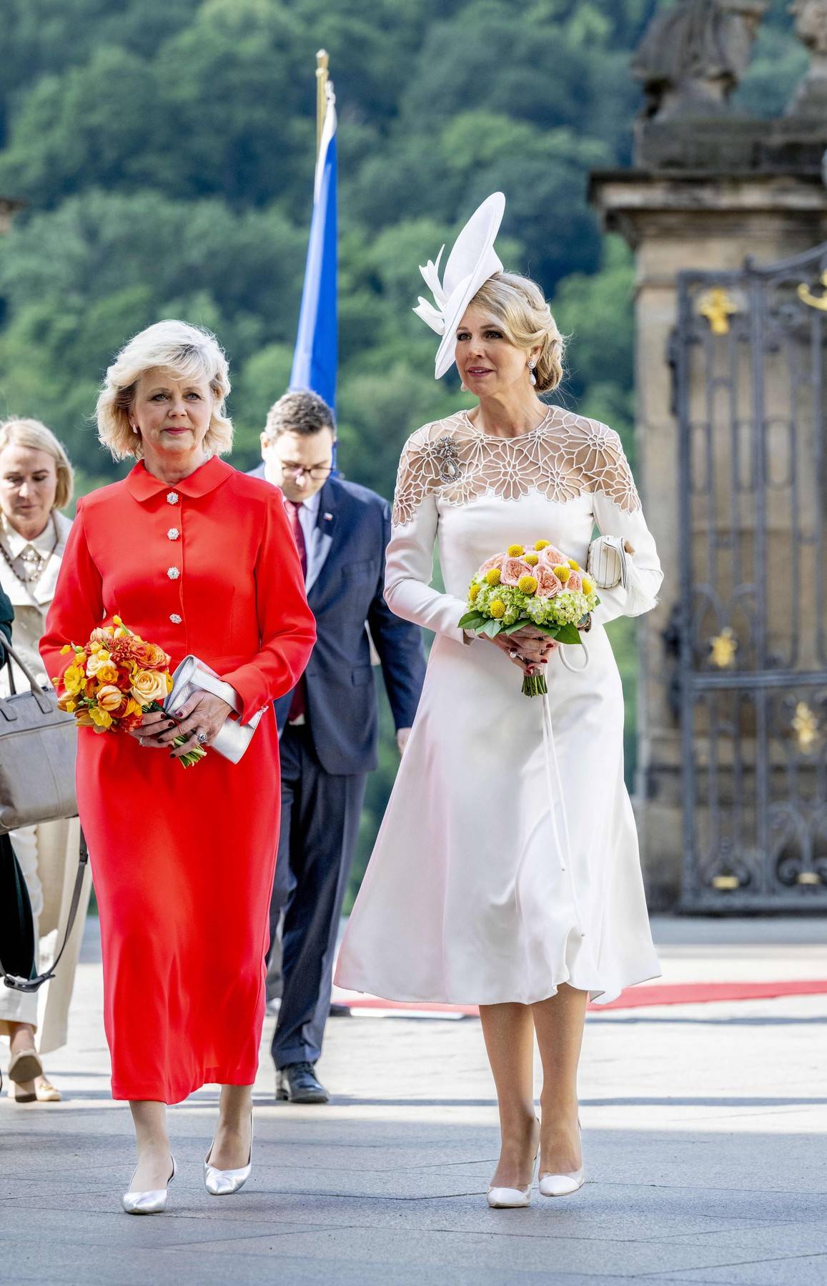 Máxima zvolila bílé šaty s krajkou v midi délce od své oblíbené nizozemské značky Jan Taminiau, zatímco první dáma České republiky Eva Pavlová vsadila na mnohem výraznější barvu. Oběma to při státní návštěvě velmi slušelo.