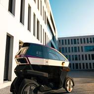 Kapotovaný elektrický skútr ÆMOTION má elektrický pohon a čtyři kola.