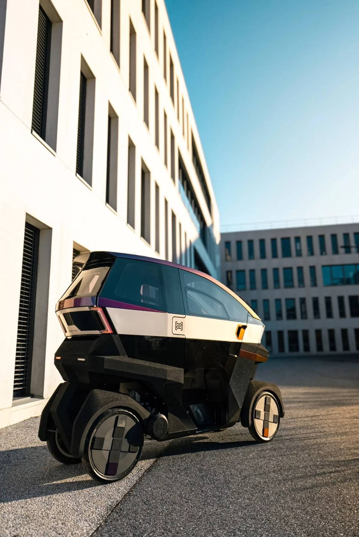 Kapotovaný elektrický skútr ÆMOTION má elektrický pohon a čtyři kola.