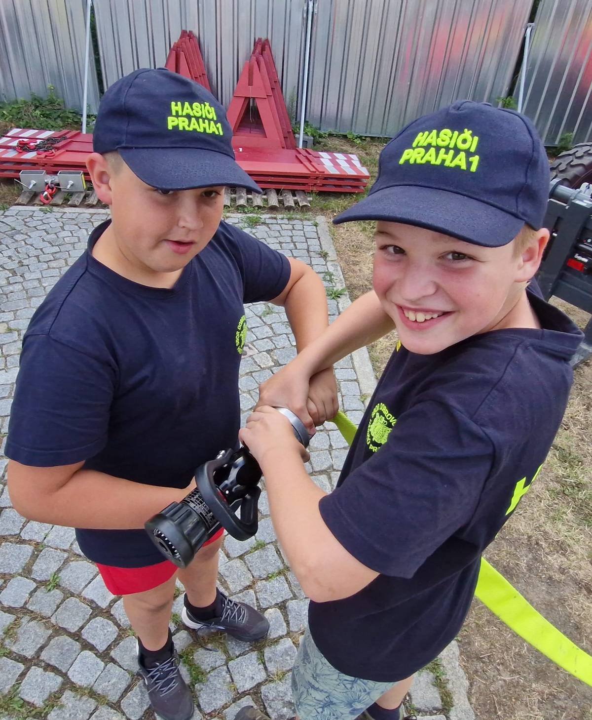 Hasiči-táborníci nasazují na hadici tzv. proudnici, která při hašení slouží k formování a usměrňování proudu vody.