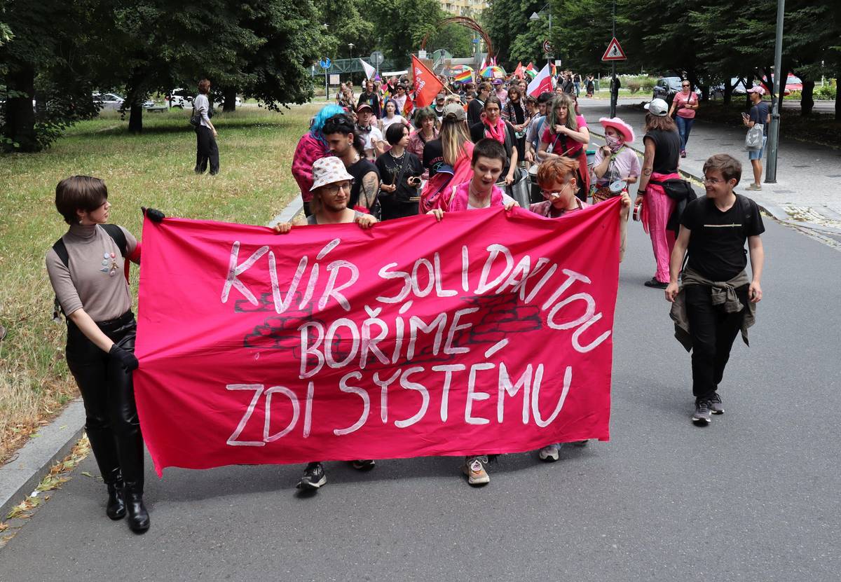 V čele průvodu nesli účastníci velký transparent s nápisem: Kvír solidaritou boříme zdi systému