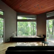 Okno s výhledem na les slouží jako promítací plátno. Čelem k němu je pak obrácená sedací souprava.