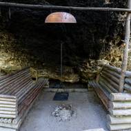 Do skály je upevněn řetěz, který drží nad ohništěm rošt na grilování.