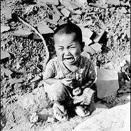 Malé dítě pláče v troskách Hirošimy.