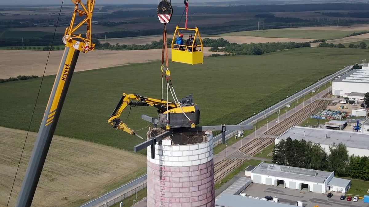 Už je skoro hotovo. Bagr zavěšený na jeřábu nadále bourá stometrový komín dukovanské elektrárny