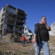 Nikola prochází kolem zničených domů.