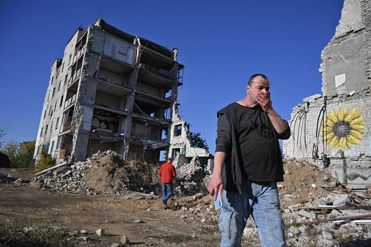 Nikola prochází kolem zničených domů.