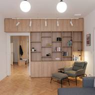 Knihovna má hravé uspořádání polic. Praktickým prvkem je křeslo umístěné v jejím těsném sousedství. Člověk to z něj pro knihu nemá daleko.