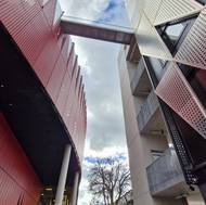 Součástí projektu Horácké arény je i sousední nárožní objekt se stříbrnou fasádou, přístup na atletický ovál na střeše zajišťuje lávka.