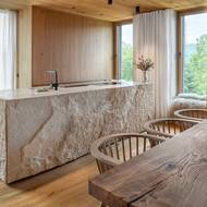 Kamenem obkládaný kuchyňský ostrůvek je hezkým protipólem okolního dřeva.