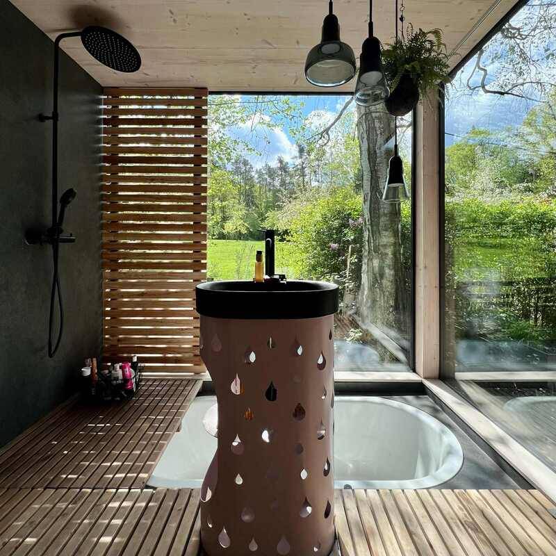 Koupelnu s vestavnou vanou propojují s venkovní přírodou velká bezrámová okna. Podstavec pro umyvadlo vytvořil na míru sochař Michal Trpák.