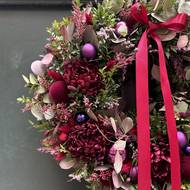 Věnec na venkovních dveřích. Základ je z pistácie, eukalyptu, dozdobený je látkovými květinami. Dotek Vánoc mu dávají skleněné kuličky.