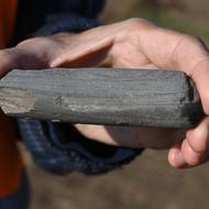 Úlomek kamenné sekery staré asi sedm tisíc let