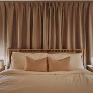 Hezkým nápadem je využití kožených poutek jak k uchycení čalounění v čele postele, tak coby úchytek na nočních stolcích.