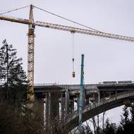 Materiál z demolované mostovky snáší jeřáby do údolí. 