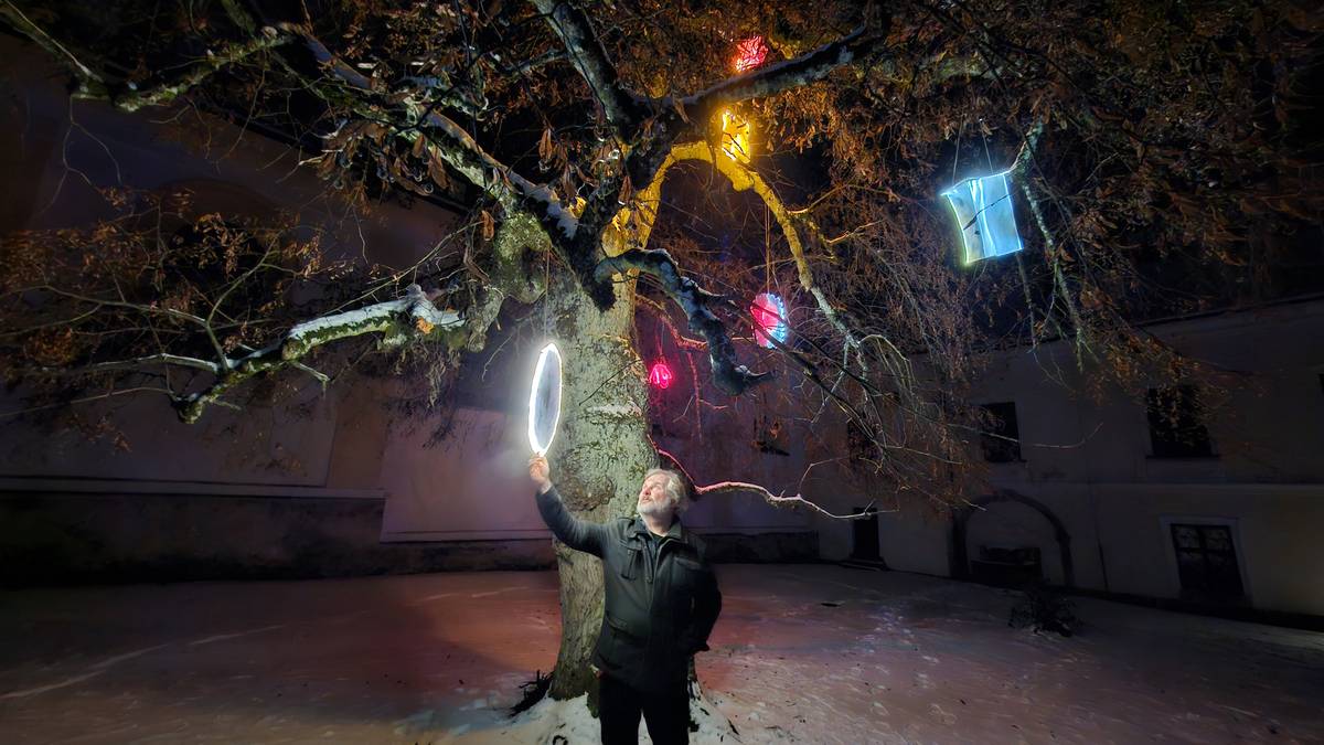 Jeden z tvůrců světelných instalací Zdeněk Durdil ukazuje originální svítící objekty umístěné na lípě.