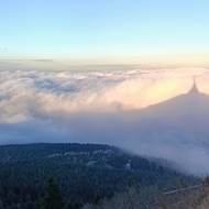 Odpolední slunce promítá siluetu Ještědu do vrstvy mlhy.