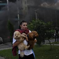 Mladá žena utíká se svými psíky před dusivým dýmem, který zachvátil Charkov po ruském útoku klouzavými bombami 24. července 2025.