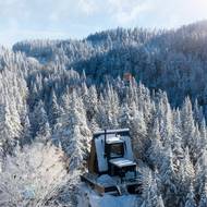 Chata se v okolních lesích skoro ztrácí.