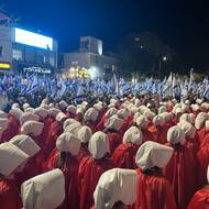 Na výstavě Umění aktivismu najdou diváci i fotografii z demonstrace v Haifě v roce 2023. Ženy v kostýmech odkazujících na dystopický seriál Příběh služebnice protestují proti snaze ultraortodoxních stran vylučovat ženy z veřejného života.