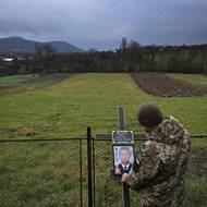 Ukrajinský voják připevňuje portrét padlého Ivana Dovhanyče na kříž, který bude stát hrobě ve vsi Veliki Lazy. 