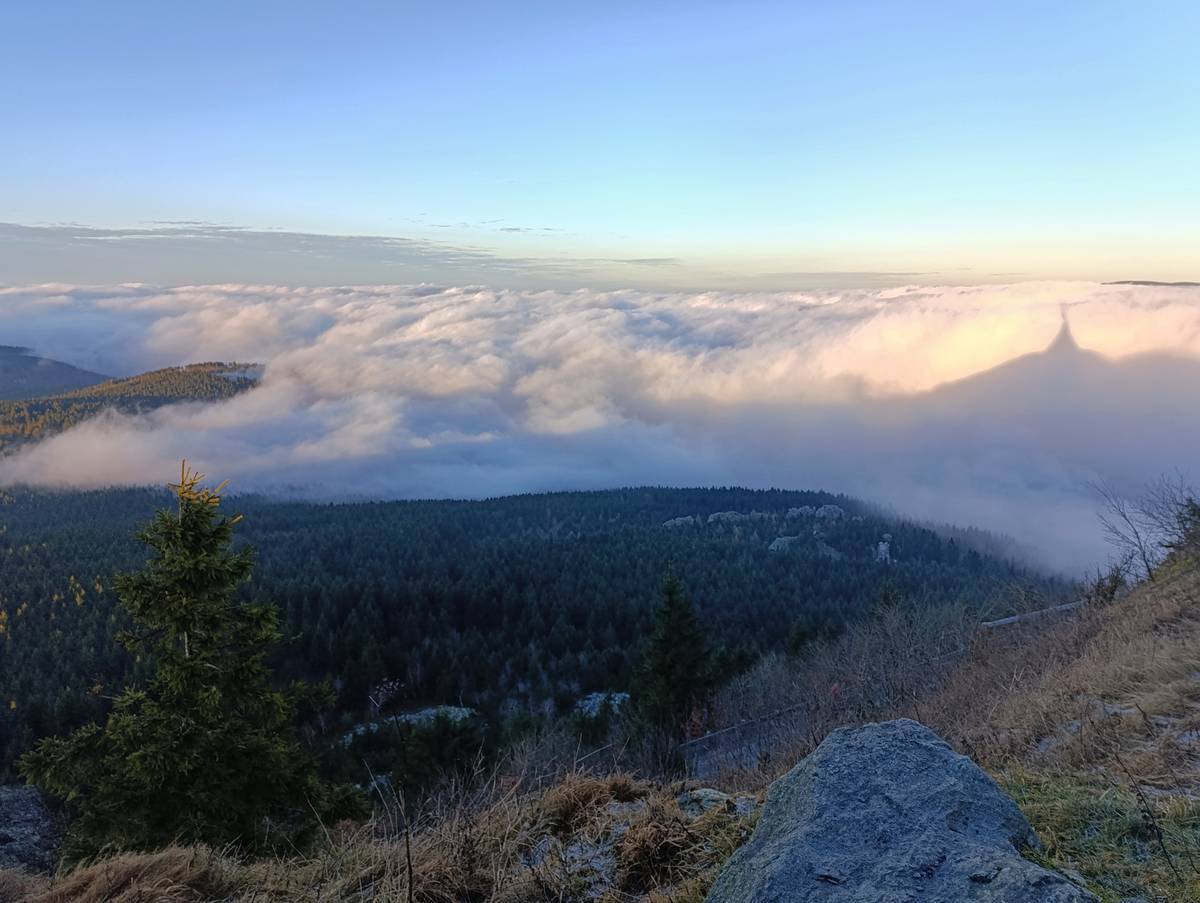 Odpolední slunce promítá siluetu Ještědu do vrstvy mlhy.